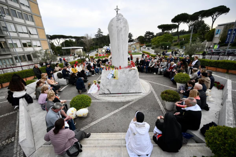 Un grupo de peregrinos rusos se reúne junto a la estatua de Juan Pablo II en la entrada del Hospital Gemelli, donde está hospitalizado el Papa Francisco
